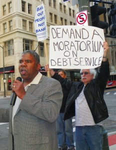 David Sole (r) holds sign while Rev. Charles Williams Sr. addresses rally against banks May 9, 2012.