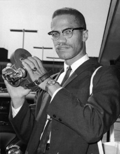 Portrait of American political activist and radical civil rights leader Malcolm X (1925 - 1965) as he holds an 8mm movie camera in London Airport, London, England, July 9, 1964. Shortly after breaking his affiliation with the Nation of Islam, and just days after his formation of the Organization of Afro-American Unity (OAAU), Malcolm X was in London en route to Egypt to attend a meeting of the Organization of African Unity and to meet with the leaders of various African states. (Photo by Express Newspapers/Getty Images)