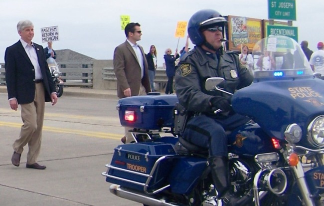 "Fascist:" Snyder on his way into Benton Harbor, the first victim of Public Act 4, on May 7, 2011. Hundreds protested.