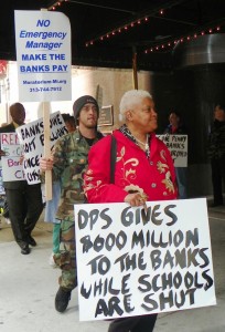 Maureen Taylor carries sign re: DPS during protest against banks' role in decay of Detroit and its schools May 9, 2012.