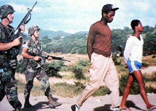 U.S. soldiers with captive citizens of Grenada, a predominantly Black, socialist-led country..