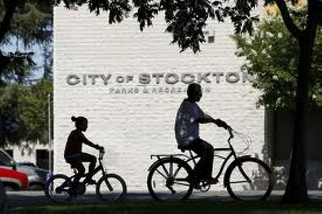 Children ride their bikes past a City of Stockton recreational building.