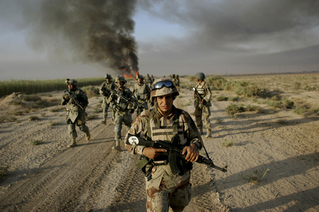 An Iraqi army soldier, accompanied by U.S. army soldiers from Fox Troop, Sabre Squadron, 3rd Armored Cavalry Regiment, walks down a field as plumes of smoke rise from a burned irrigation canal in a deserted area on the outskirts of Balad Ruz, in Iraq's Diyala province, some 75 kilometers ( miles) northeast of Baghdad, Iraq, Sunday, Aug. 10, 2008. Soldiers from Fox Troop burned thick growth inside irrigation canals as they were searching for weapons caches in the area. (AP Photo/Marko Drobnjakovic)