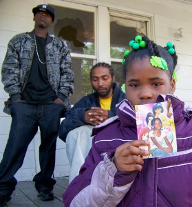 Aiyana's grieving classmate Diamond Hardy, 7, shows photo as father grieves in front of shattered window  Photo by Diane Bukowski