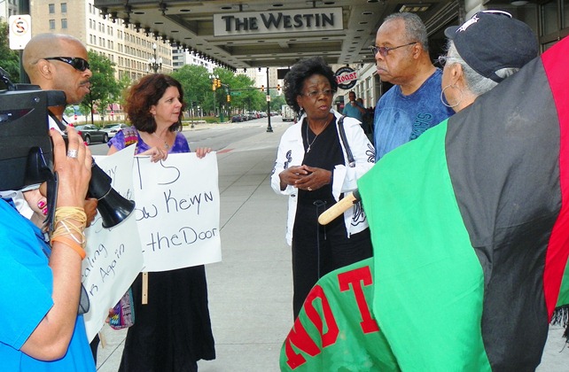 Detroit city retiree and union rep Carrie Williams (center) with husband at her left, speak with protesters.