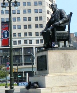 Homeless man in Detroit rests at base of Mayor Hazen Pingree statute. The plaque on the statue says Pingree was the first to warn of the dangerous powers of the private corporations.