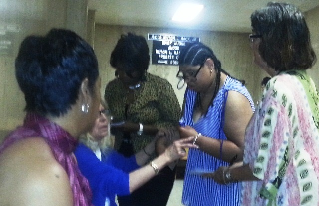 Newly-appointed GAL Mary S. Rowan (seated in blue dress) grabs Maulauni Williams' arm as she berates VOD reporter (r) for covering the story in the courtroom. Pamela Reid of Faith Connections is at left, with Mailauni's sister Monique Williams at center. The day after the hearing, Rowan seized Mailauni from Reid's group home. Her whereabouts are currently unknown.