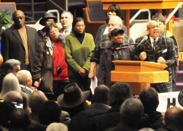 Rev. Pinkney (r) speaks at first mass rally against Emergency Manager Law Public Act 4, later repealed and replaced with PA 436. Rally of thousands was held at New Triumph Baptist Church in Detroit.
