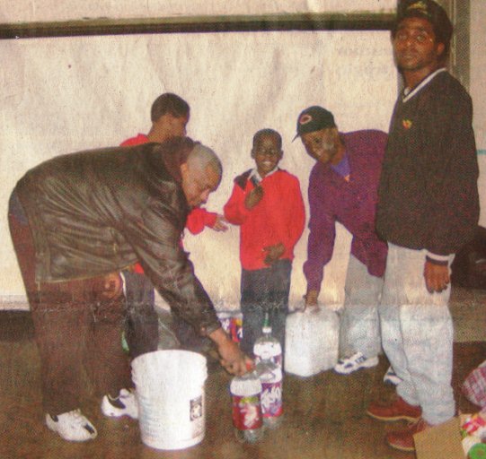 Frank Lewis delivers water to his neighbors, 10 year old Edward Jones, 6 year old Pierre Cook and their parents Marilyn Cook and Edward jones during wave of water shut-offs in 2002.
