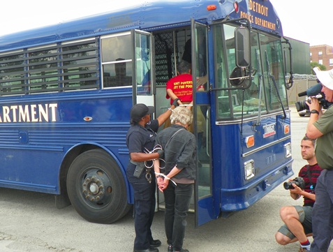 Marian Kramer (in red T-shirt proclaiming "Fight Poverty, Not the Poor," is arrested and put on police bus.