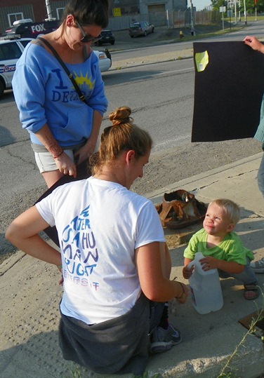 Child protester smiles at mom as he quenches thirst on Homrich blockade July 18, 2014.
