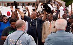 Protesters raise hands, imitating Michael Brown's stance while a Ferguson, MO police officer shot him to death, causing outrage in the community,
