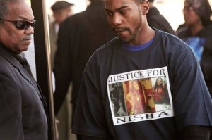 Friend attends McBride's funeral wearing "Justice for Nisha" T-shirt. She was a graduate of Southfield High School and an employee of Ford Motor Company.