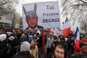 A demonstrator holds up a sign portraying French President Francois Hollande wearing donkey ears with a school grade of Zero and which reads, "You, President Resign." Photo: Reuters