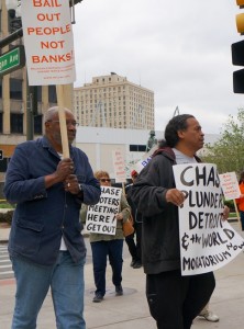 Abiyomi Azikiwe of Moratorium NOW! and Bill Davis, Pres. of the Detroit Active and Retired Employees Association, marched on Chase meeting. In background is Kris Hamel of Moratorium NOW! telling Chase to leave Detroit. /Photo: Stephanie Gordon