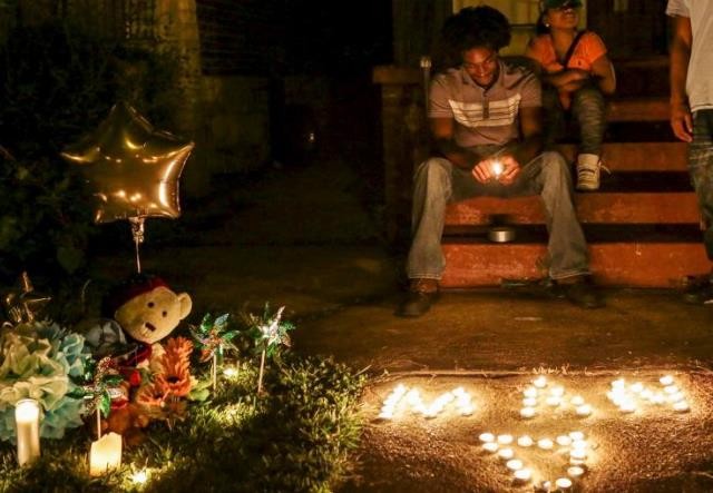 Chris Ball-Bey, the brother of Mansur Ball-Bey, sits by his brother’s memorial after a candlelight vigil on Walton Ave in St Louis on Thursday. Photograph: Lawrence Bryant/Reuters