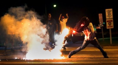 Demonstrator in Ferguson throws tear gas canister back at police, in aftermath of police killing of Michael Brown Aug. 9, 2014.