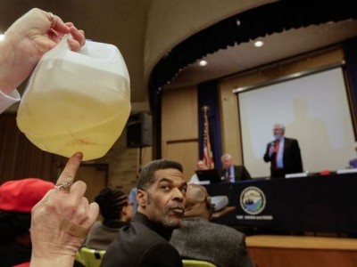 Flint resident holds up jug of contaminated water during hearing.