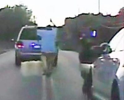 Terence Crutcher walks toward his car with his hands up, followed by cops.