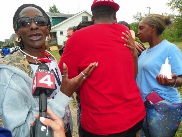 Children's great-grandmother Marie Jackson speaks to news at vigil as neighbor hugs children's mother Alisha Jackson.