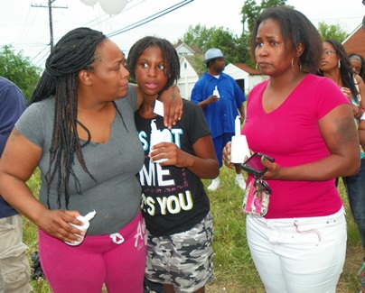 Mother holds child tightly during candlelight vigil June 26 at Jackson family home.