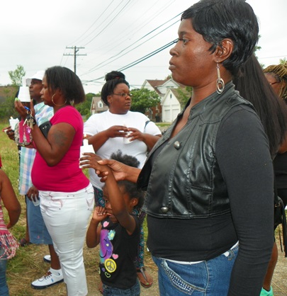 Mother holds her child's hand tightly during vigil. Is it safe for Detroit's little children to be on the streets in front of their own homes?