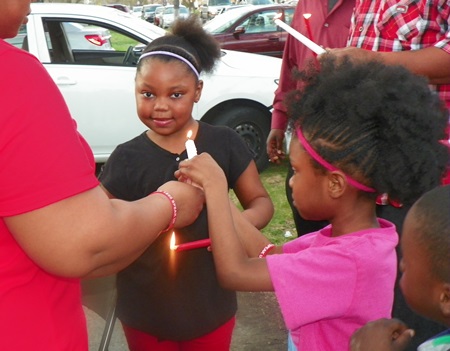 Children help each other light candles.
