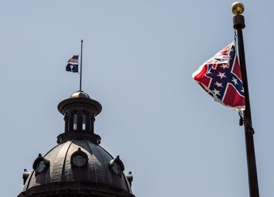 The South Carolina and U.S. flags fly at half staff at state capitol as the Confederate flag unfurls at full staff at the Confederate Monument nearby, in Columbia, SC. Sean RayfordGetty /Images 